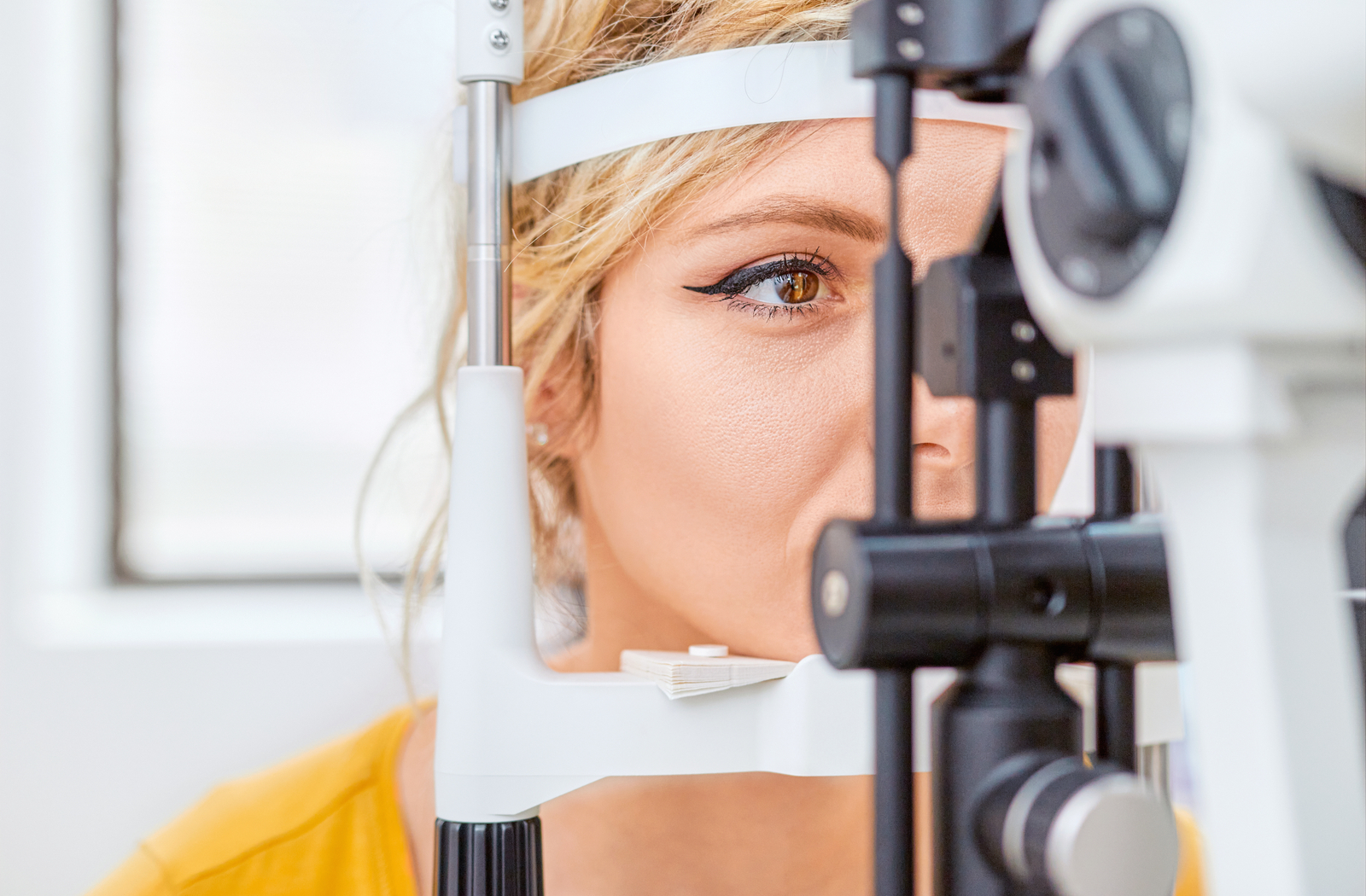 Optometry patient with their head resting in a slit lamp machine while eye doctor looks through the microscope