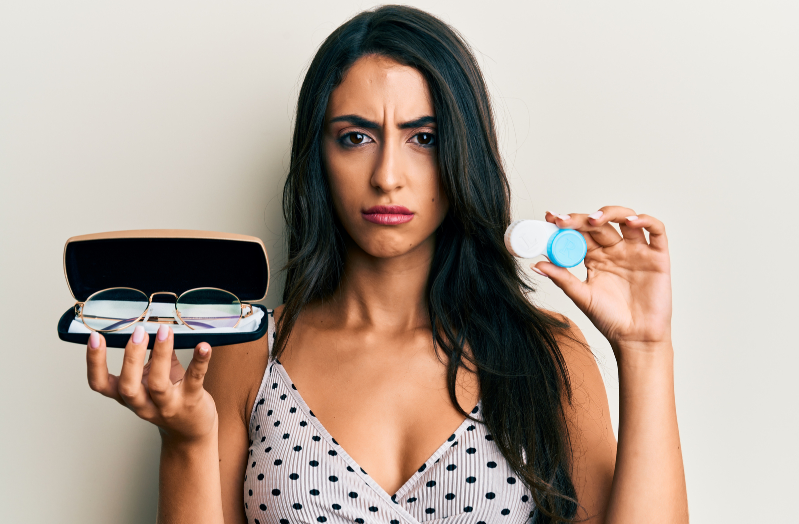 Confused looking women deciding between glasses or contact lenses