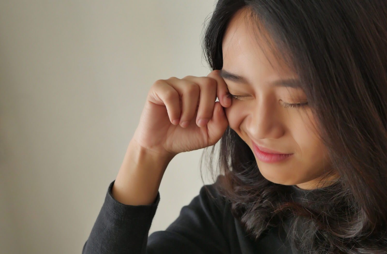 A close-up of a young woman rubbing her right eye with her right hand, feeling eye discomfort after wearing her contact lens inside out.