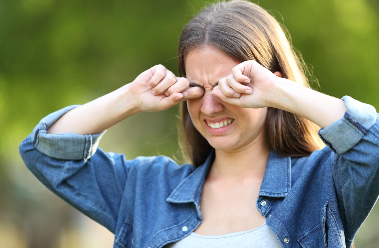 Woman scratching her eyes and wincing in pain because of dry eyes