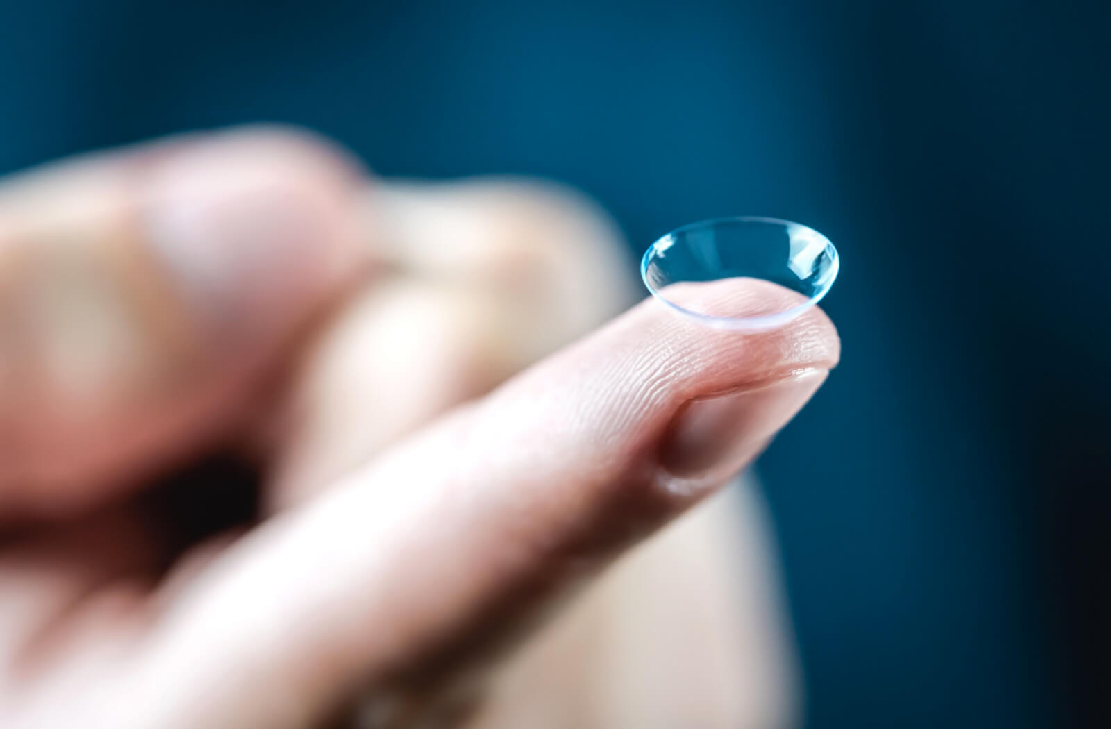 A close-up of a multifocal contact resting on a person's index finger.