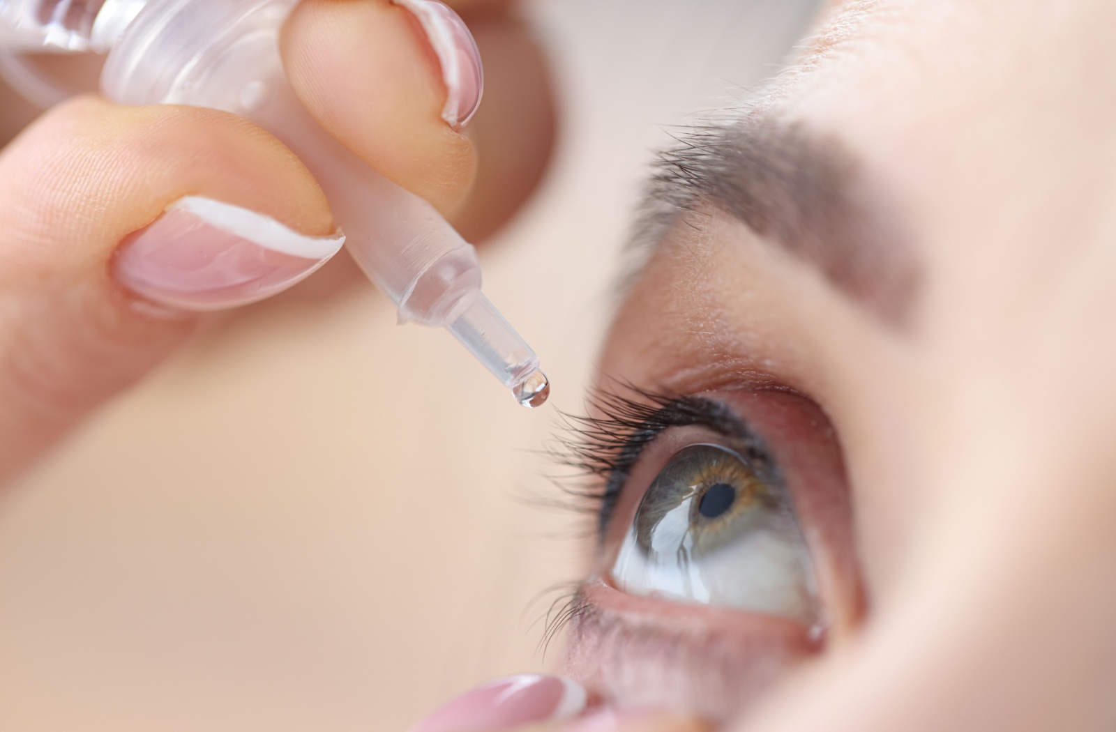 A close up of a woman's eye as she applies lubricating eye drops for dry eye.